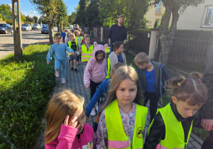 Dzieci z grupy "Biedronek" spacerują chodnikiem.