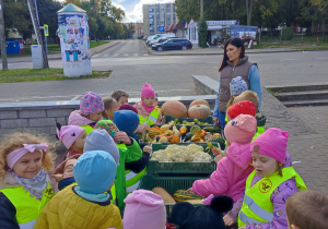 Dzieci stoją przy skrzynkach z warzywami.