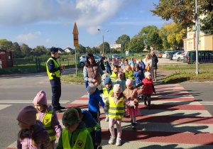 Dzieci przechodzą po biało – czerwonych pasach na jezdni.