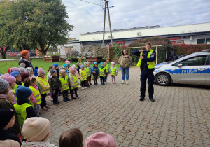 Pan Policjant zakłada kamizelkę odblaskową.