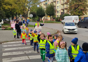 Pan Policjant zatrzymuje auta, dzieci przechodzą przez przejście dla pieszych.