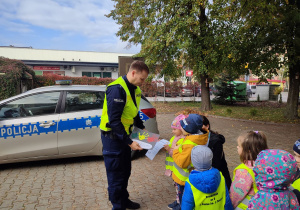 Emma i Wojtuś wręczają podziękowanie i laurkę panu Policjantowi.