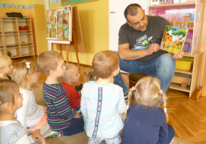 Tatuś Hani z grupy Krasnoludków czyta dzieciom bajkę o przygodach dzikich zwierząt.