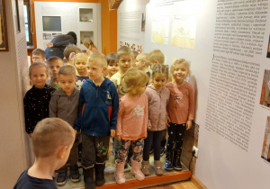 Przedszkolaki pozują do zdjęcia w sali muzealnej.