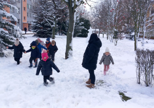 Przedszkolaki biegają po śniegu.