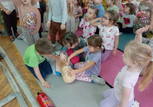 Hania, Iga i Alicja ćwiczą sztuczne oddychanie na fantomie.