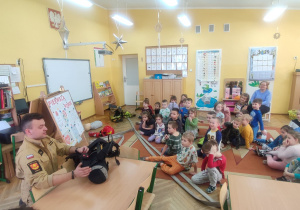 Pan Kamil pokazuje specjalną kamizelkę strażacką.