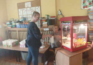 Pani Karina i Natalia sypią popcorn do torebek.