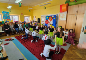 Chłopcy klęczą przed dziewczynkami na zakończenie tańca
