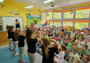Przedszkolaki oglądają występ dziewczynek z koła tanecznego