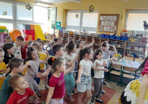 Dzieci ćwiczą na dywanie w rytm muzyki.