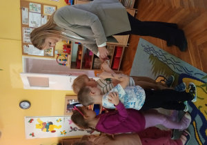 Przedszkolaki otrzymują naklejki z owocami i warzywami.