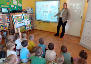 Dzieci nazywają zabawy sportowe pokazywane na tablicy interaktywnej przez prowadzącą.