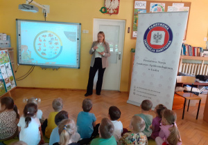Pani Patrycja, na pokazowym talerzyku, wyjaśnia dzieciom proporcje spożywanych warzyw.