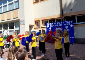 Przedszkolaki w tańcu machają pomponami.