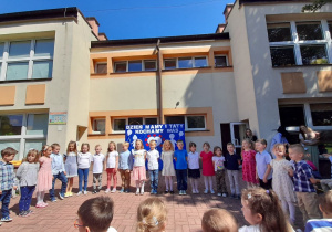 Dzieci z grupy Misiaczków stoją w półkolu i recytują wierszyk: „Dla Mamy i Taty”.