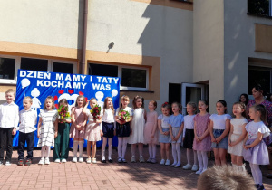 Trzy dziewczynki trzymają w ręku kwiaty.