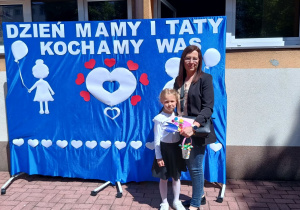 Wiktoria z mamą stoi na tle dekoracji.