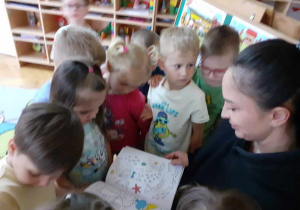 Dzieci oglądają z mamą Igi książeczkę.