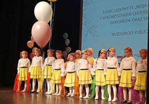Dziewczynki i chłopcy ustawione w rzędzie na scenie