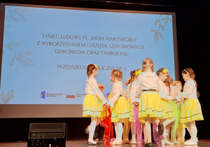 Dziewczynki w parach ustawione w kole tańczą w rytm utworu