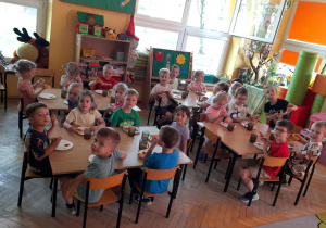 Krasnoludki zajadają się pizzą podana na podwieczorek.