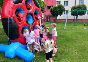 Dziewczynki z grupy „ Krasnoludków” celują piłeczkami do otworów w dużej tarczy.