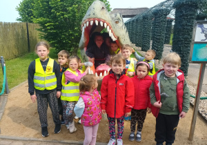 „Żabki „ pozują do zdjęcia z dinozaurem.