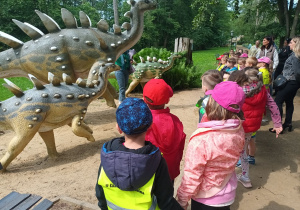 „Misiaczki” i „Żabki” oglądają figury rodziny dinozaurów.