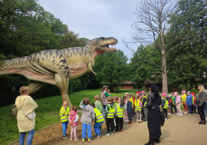 Panie i dzieci podziwiają kolejną figurę dinozaura.