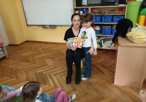 Oliwka z mamą pokazują dzieciom książeczki z bajkami, które przekazują do „ Kącika książki”.