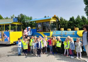 „Słoneczka” pozują do zdjęcia przed lokomotywą.