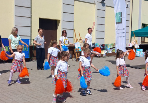 Rodzice wspólnie z dziećmi tańczą na scenie.
