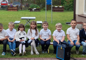 Dzieci siedzą na ławeczce przed występami.
