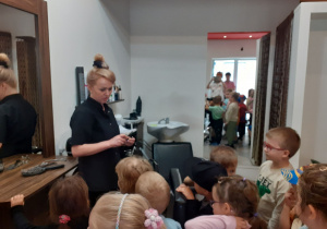 Dzieci słuchają jak Pani fryzjerka opowiada o swojej pracy.