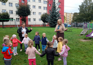 Pani Ania i Pani Monika pokazują maluszkom ustawionym w kole, grę na gitarze.