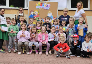 Uśmiech gości na twarzach dzieci z grupy Misiaczków, pozujących do wspólnego zdjęcia.