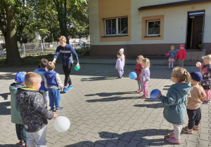 „Słoneczka” z balonami, ustawione w parach słuchają objaśnień pana Patryka.