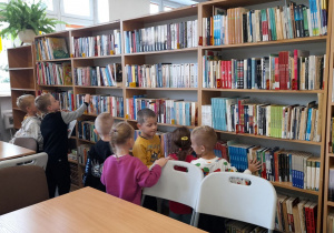 Przedszkolaki odszukują myszki, które ukryły się na bibliotecznych półkach.