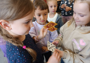 Zabawy z kartami: Anastazja z Michaliną stworzyły parę o takich samych kartach, Oliwia patrzy czy też ma parę takich samych kart.