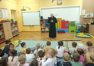 Trener Pan Paweł Bartosik opowiada dzieciom o swojej pasji (wschodnich sztukach walki), prezentuje strój i miecze - do ćwiczeń i walki.