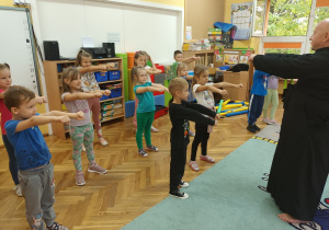 Dzieci pod okiem trenera wykonują ćwiczenia karate.