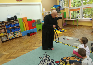 Dzieci oglądają czarny pas trenera, który tłumaczy co oznaczają znaki na nim.