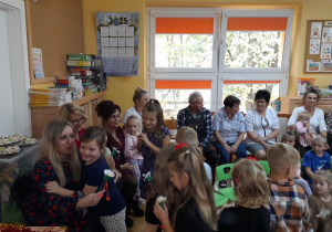 Dzieci wręczają pracownikom kwiaty.