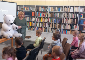 Pani Urszula prezentuje dzieciom białego dużego misia pluszowego