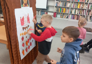 Chłopcy ozdabiają tort urodzinowy dla misia.