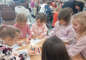 Dziewczynki kolorują obrazki z Kubusiem Puchatkiem.