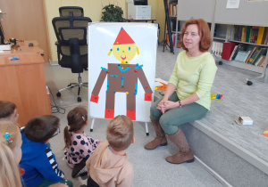 „Krasnoludki” wraz z Panią Iloną podziwiają ułożonego przez siebie pajacyka z figur geometrycznych.