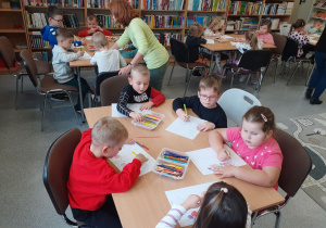 Przedszkolaki przy stolikach kolorują owocowe rytmy.