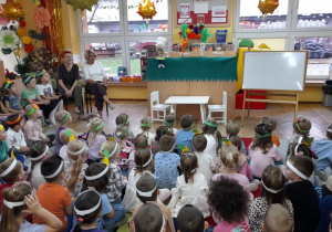 Dzieci siedzą na dywanie i oglądają teatrzyk: „O marchewce i pietruszce”.